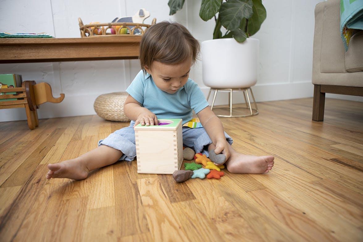 Toddler using the Magic Tissue Box by Lovevery with rocks