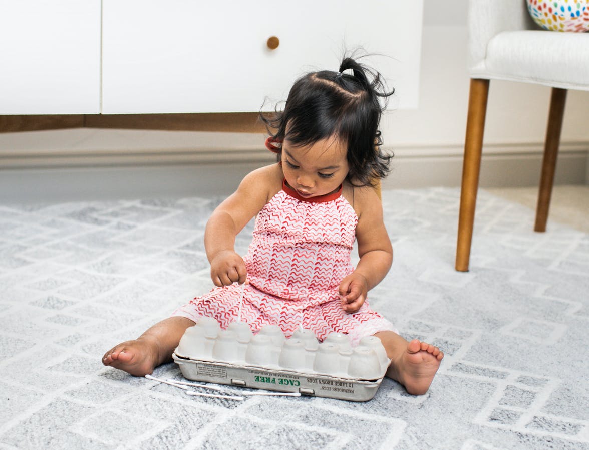 Toddler putting q-tips into an egg carton