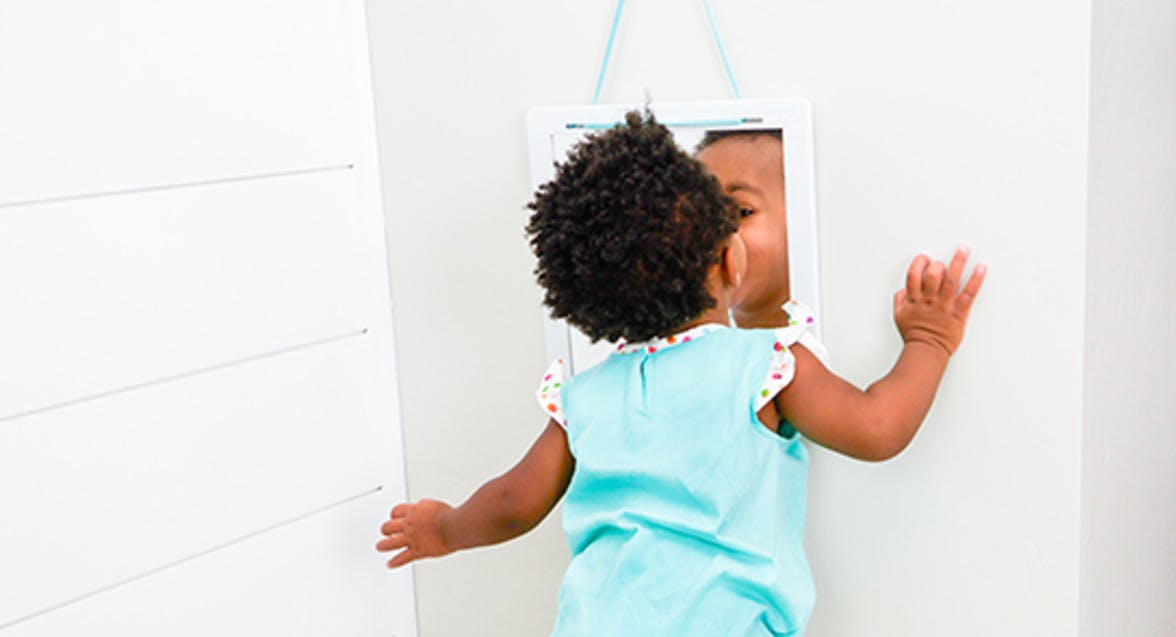 Toddler looking into a mirror at themselves
