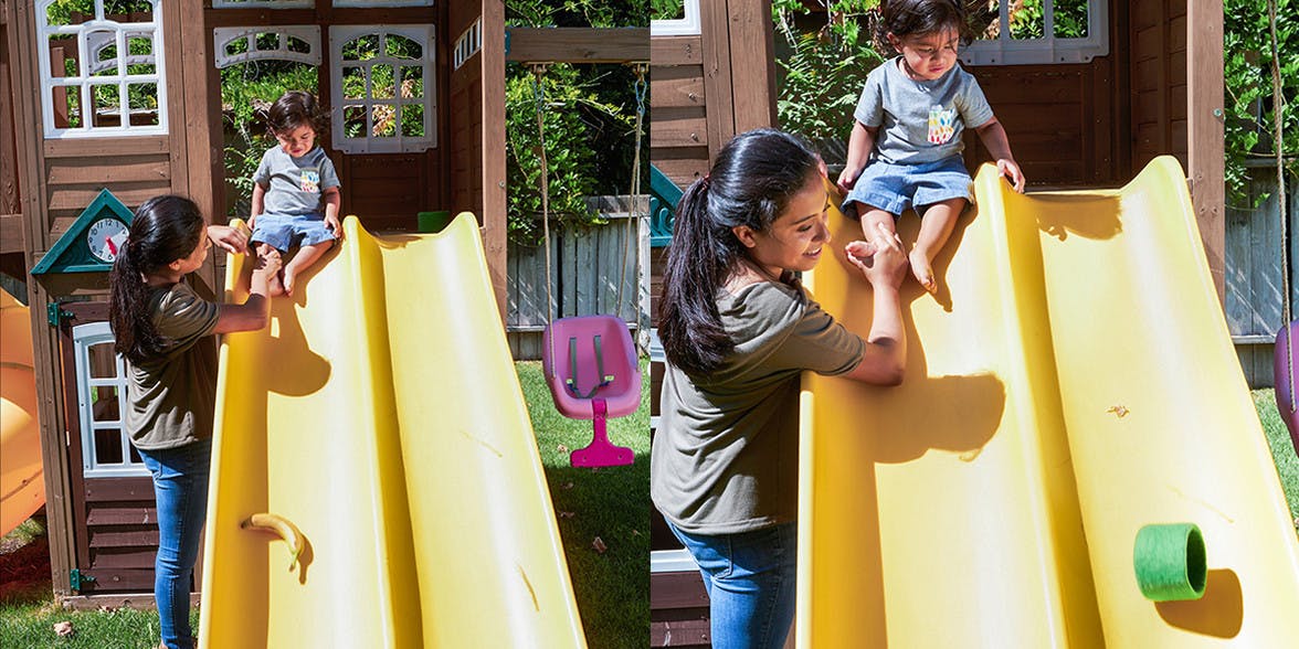 Woman helping a toddler down a yellow slide