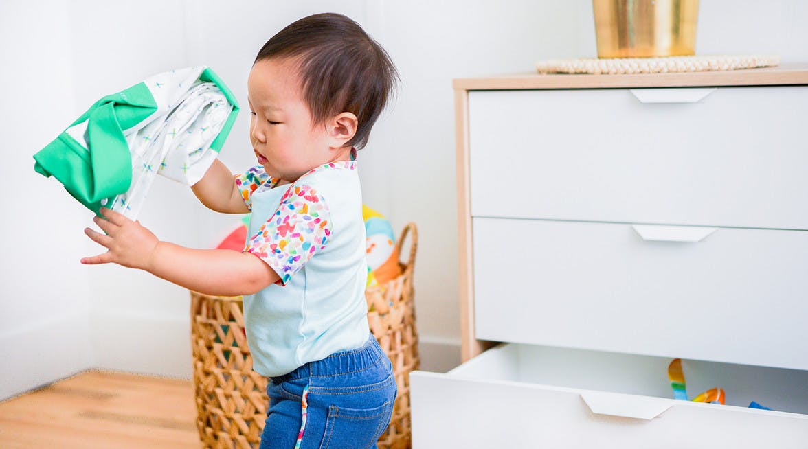 Toddler taking clothes out a dresser drawer