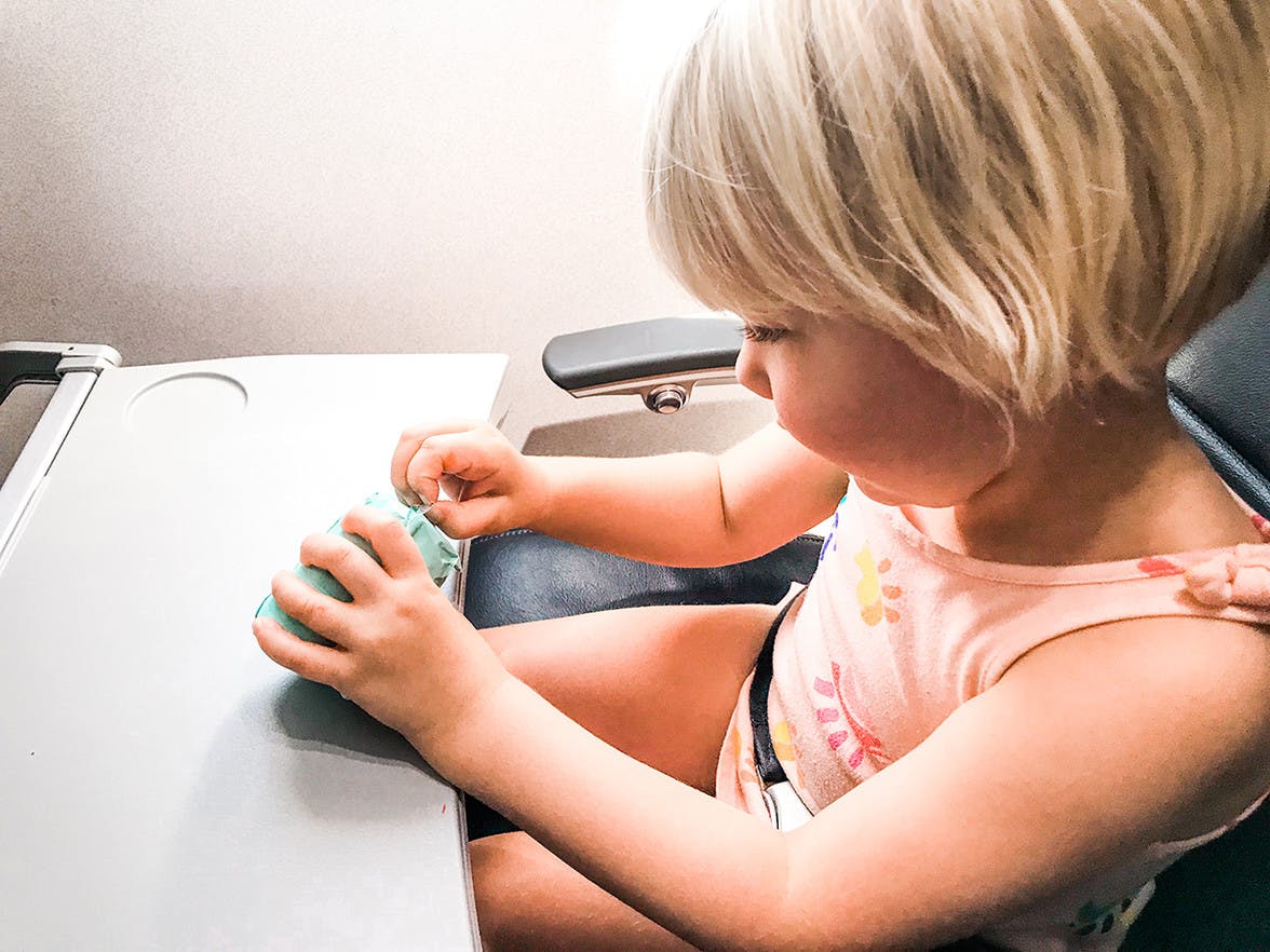Child sitting in an air plane seat opening a toy