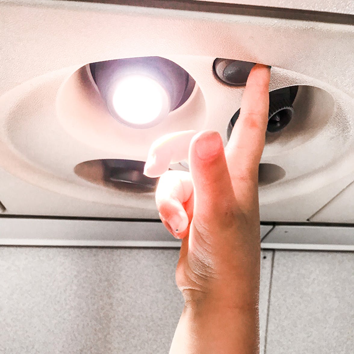 Child playing with the light switch and fan buttons on an air plane