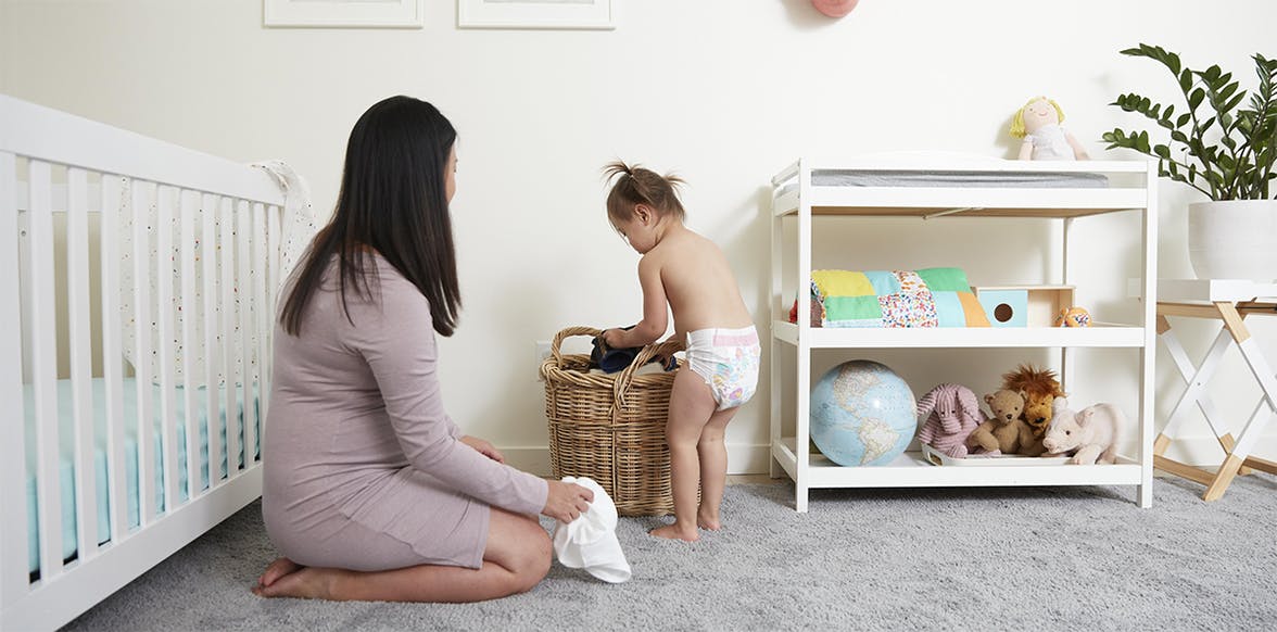 Young child putting clothes in a laundry hamper in their room