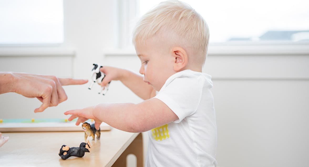 Toddler playing with animal figurines at a table