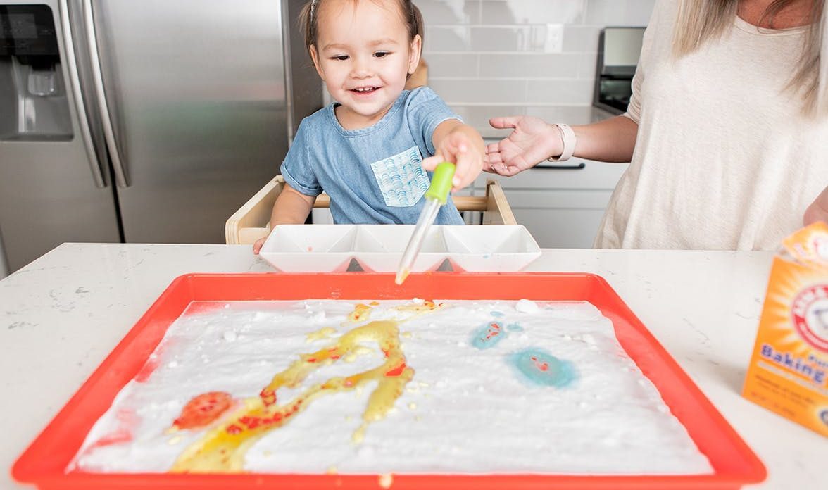 Child doing a DIY STEM activity with baking soda, food coloring, and water.