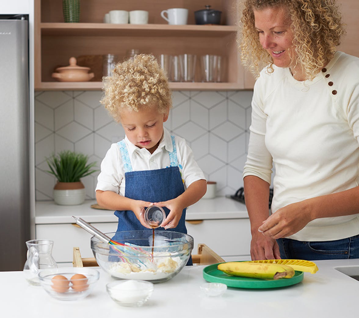 Toddler pouring vanilla into a mixing bowl