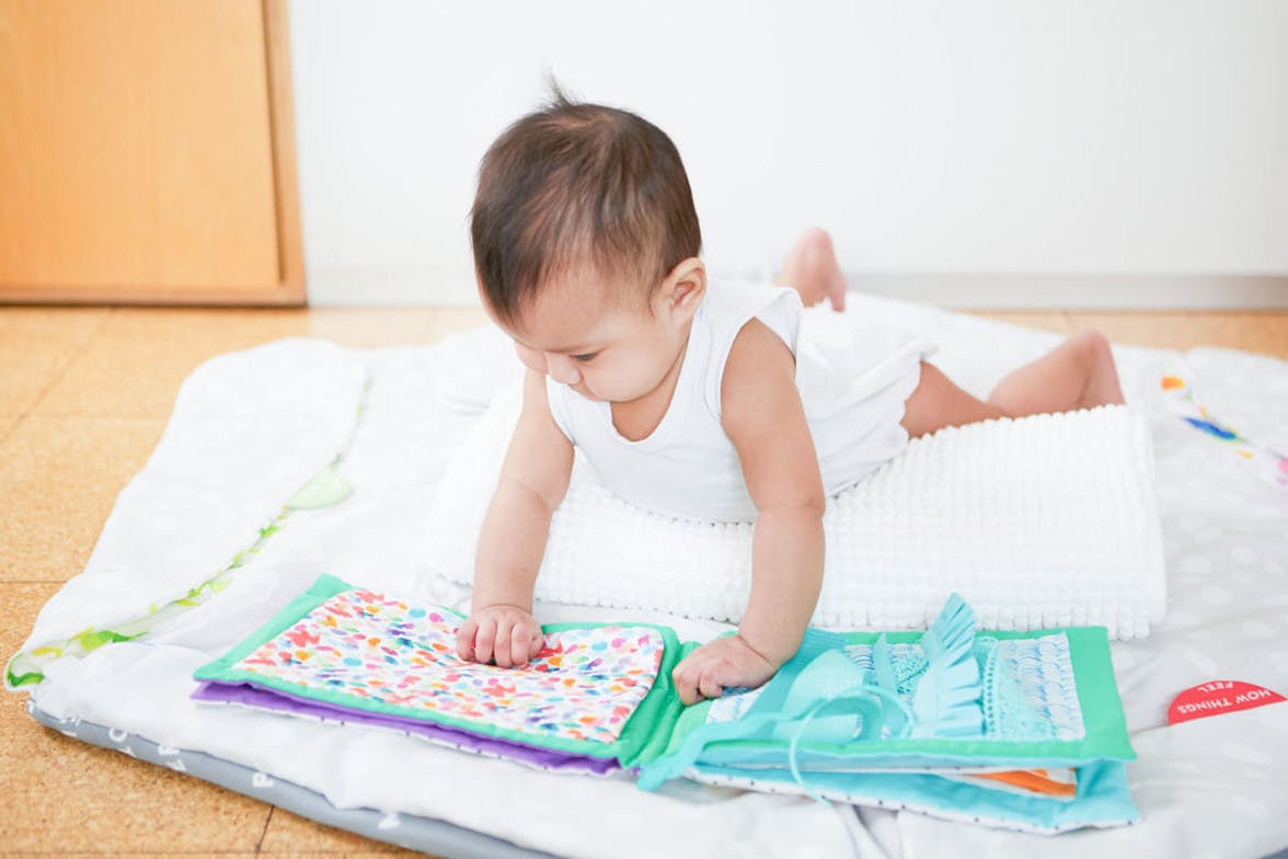 Baby doing tummy time while looking at a colorful textured book