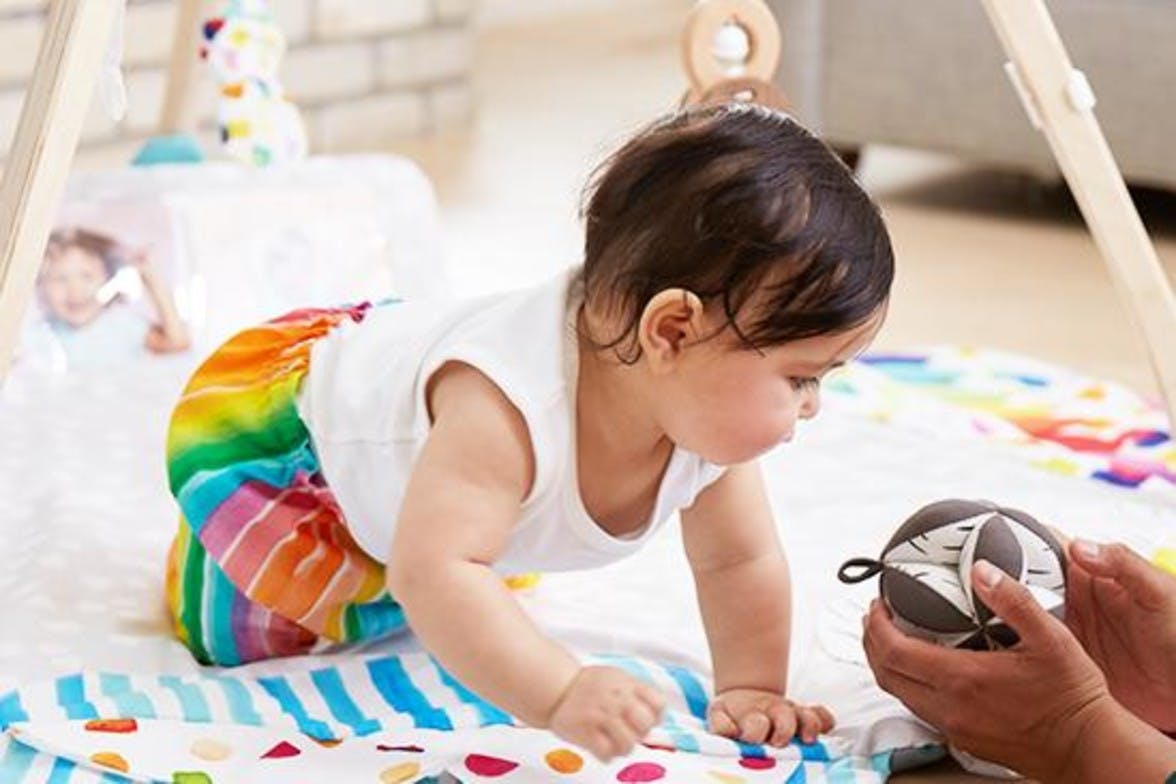 Baby playing under the Play Gym by Lovevery