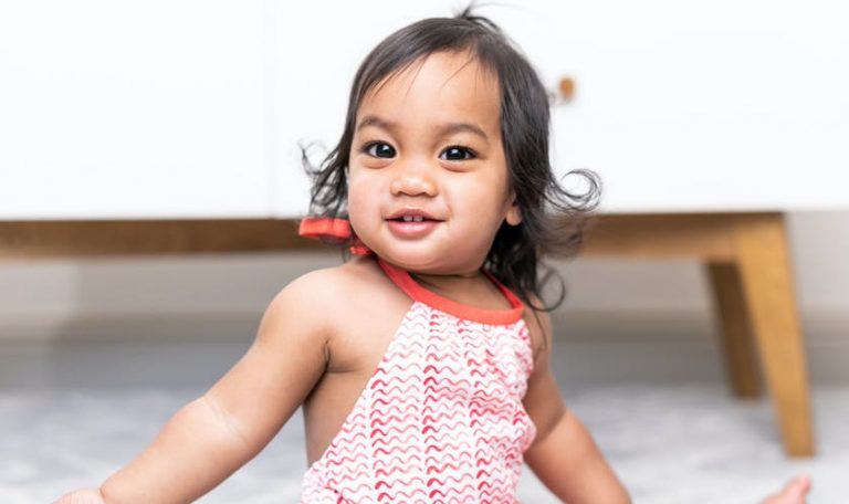 Toddler smiling and wearing a red and white dress