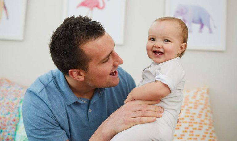 Man holding up a baby who is smiling