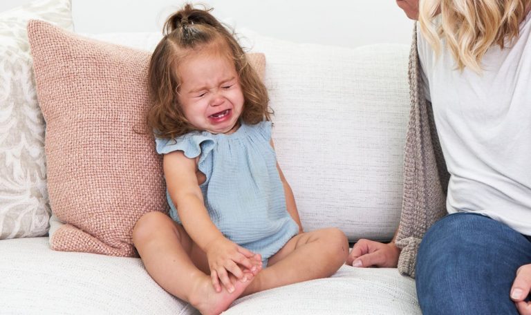 Toddler sitting on the couch upset and crying