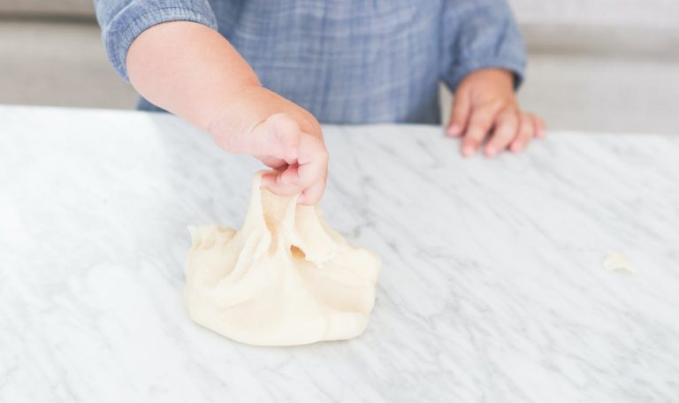 Baby playing with dough at the kitchen counter