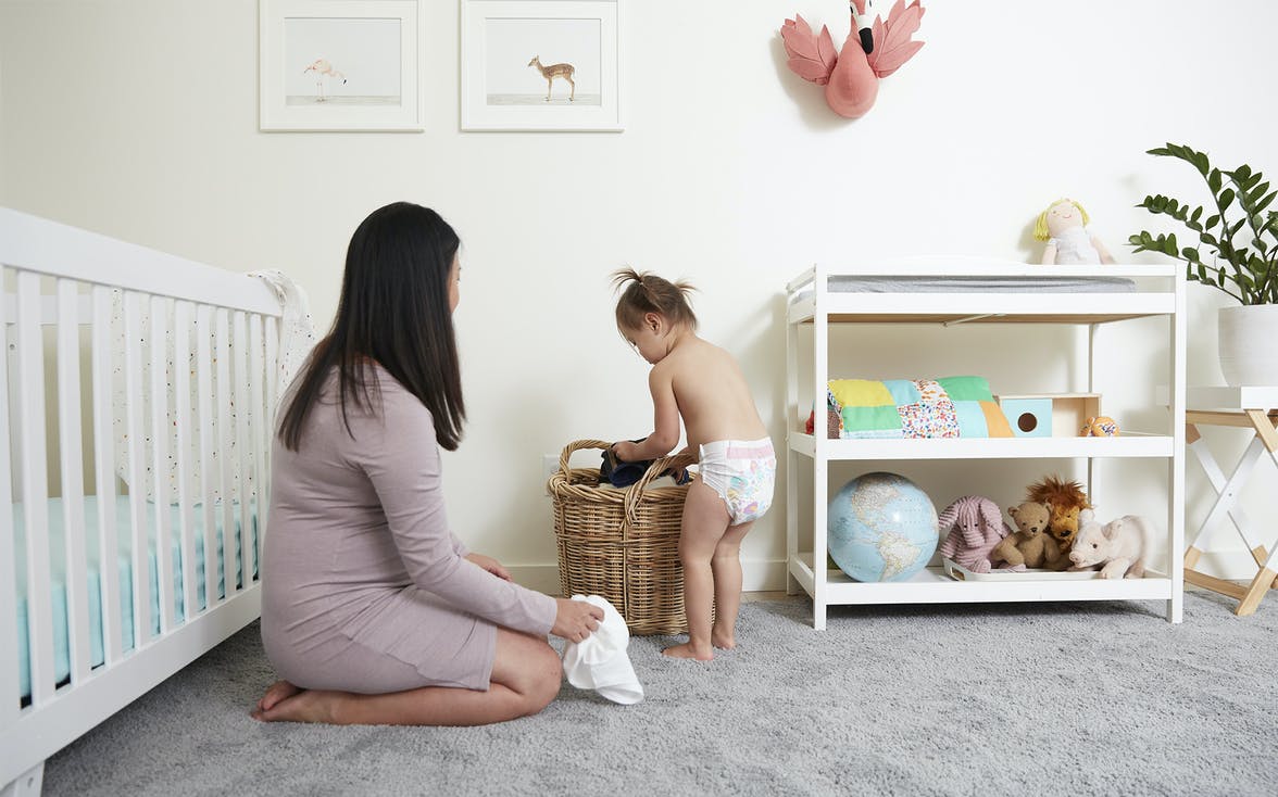 Young child putting clothes in a laundry hamper in their room