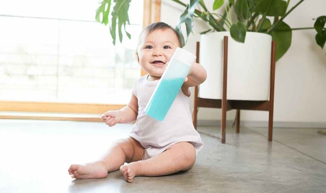 Baby holding water bottle filled with blue soapy water