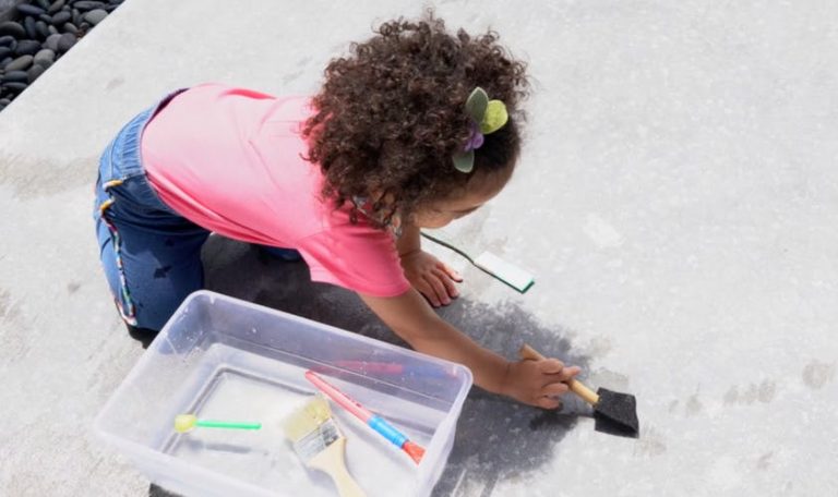 Young child painting a sidewalk with water