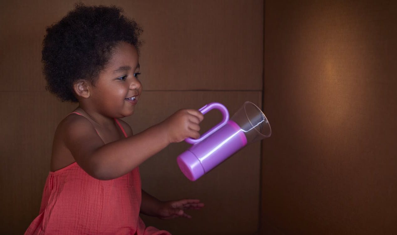 Toddler using the Lovevery flashlight against a wall