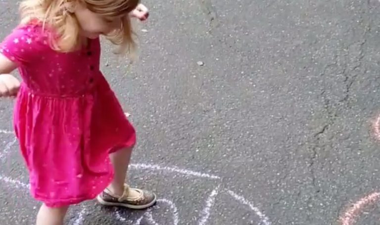 Young child playing hopscotch outside