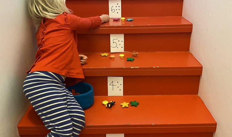 Young child sitting on stairs that are numbered