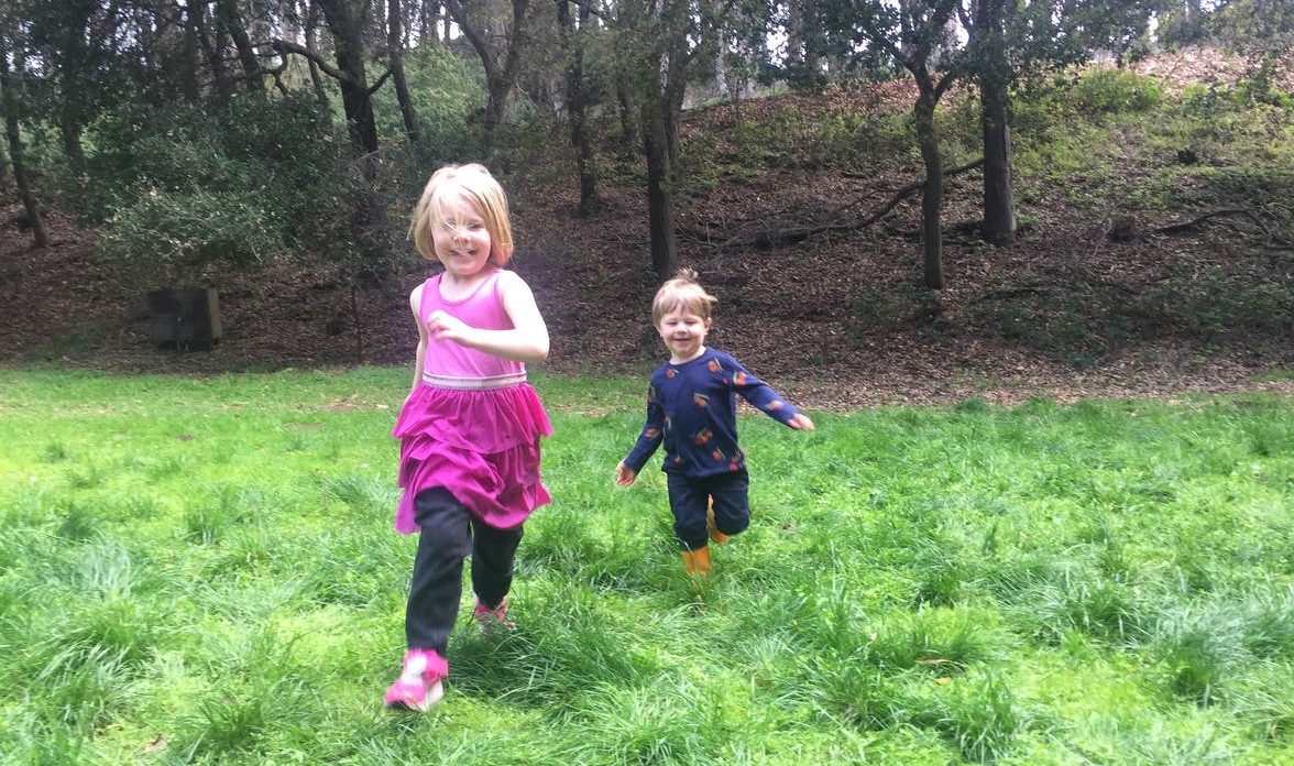 Two young children running in the grass outside