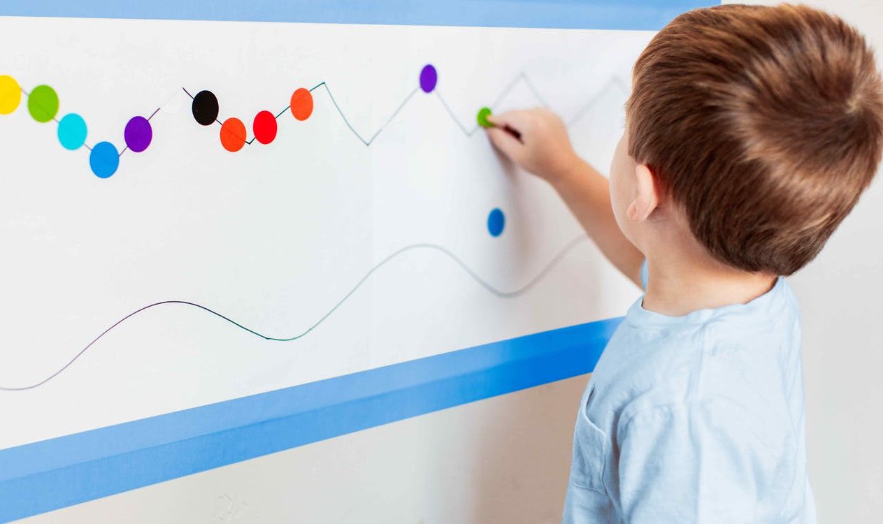 Young child putting stickers on a large piece of paper