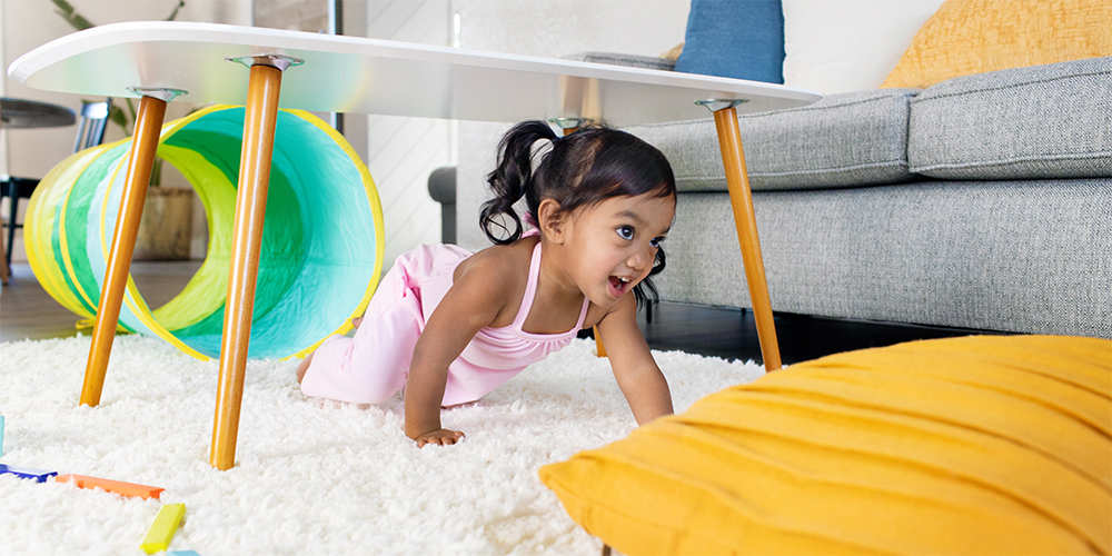 Young child crawling under a table in a home made obstacle course
