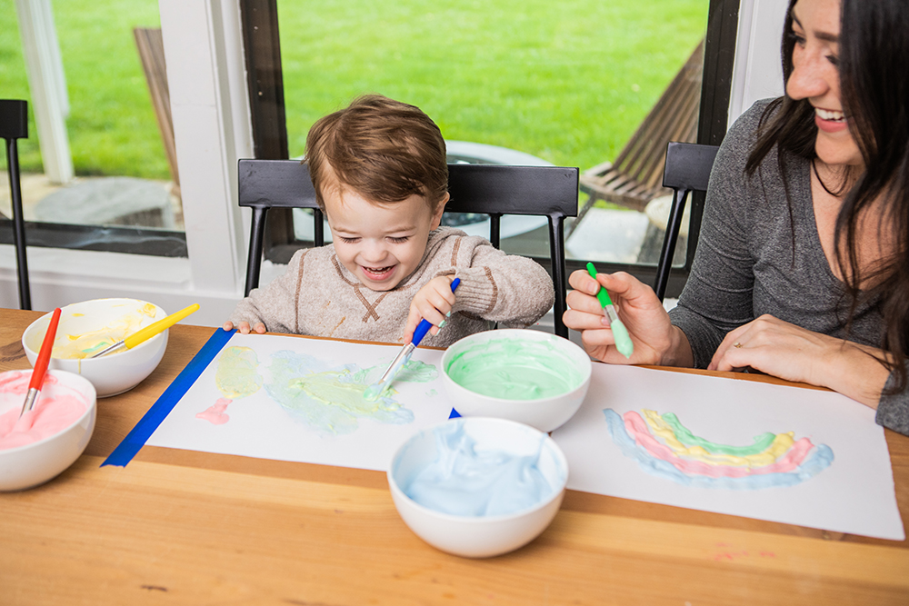 Woman and toddler playing with colored shaving cream on a piece of paper