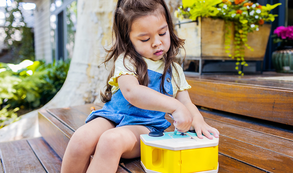 Young child playing with the Wooden Camper with Locking Doors by Lovevery