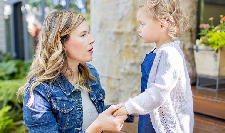 Woman looking at a toddler holding her hands