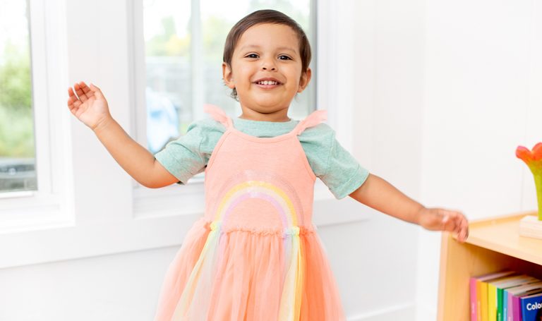 Child wearing a rainbow dress.