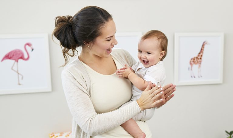 Woman holding a clapping baby on her hip