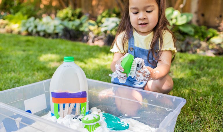 Child plays with suds in a water table.