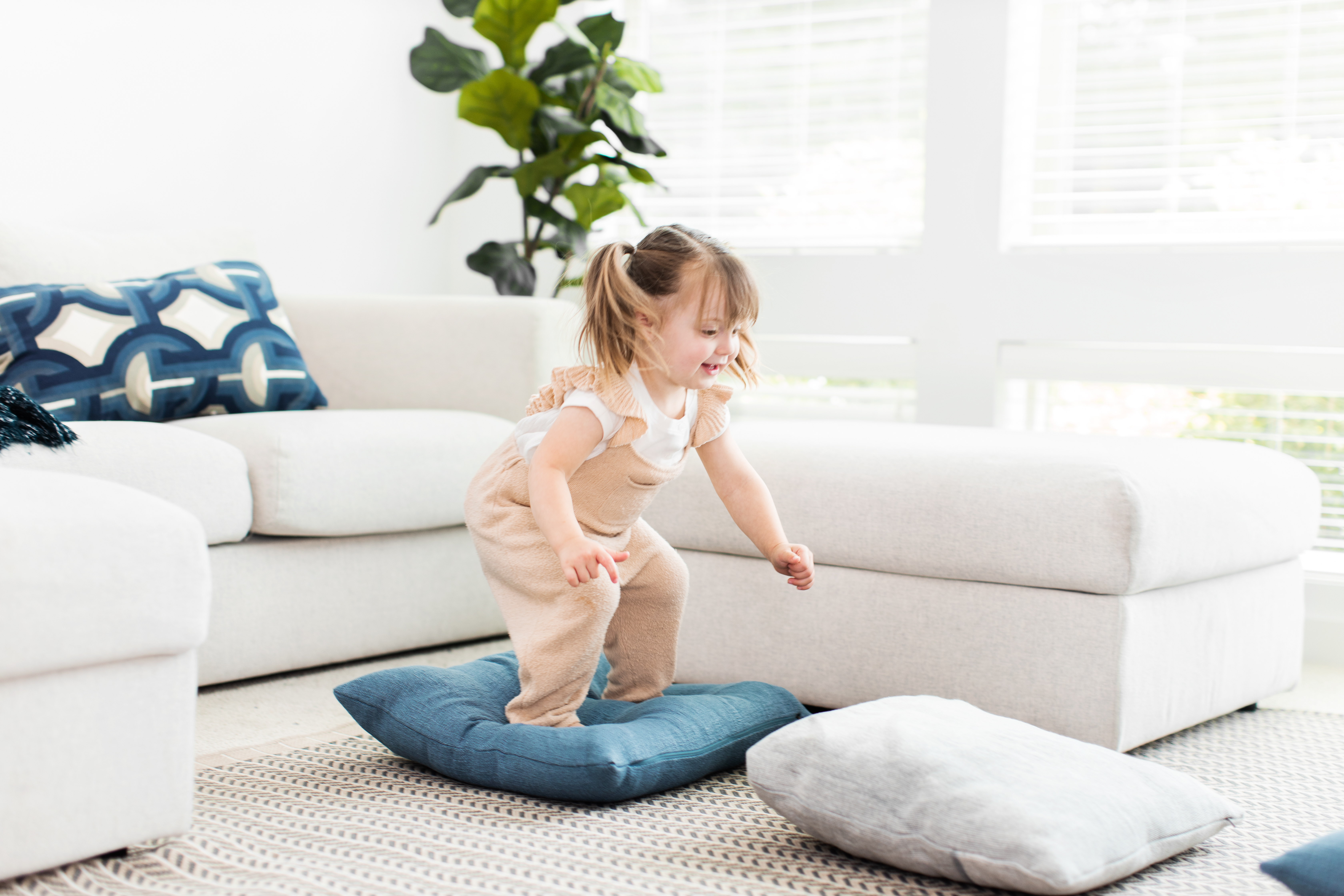 Toddler jumping from a pillow to another pillow on the ground