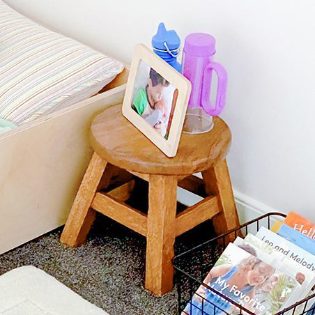 Wooden stool with picture frame and flashlight on it