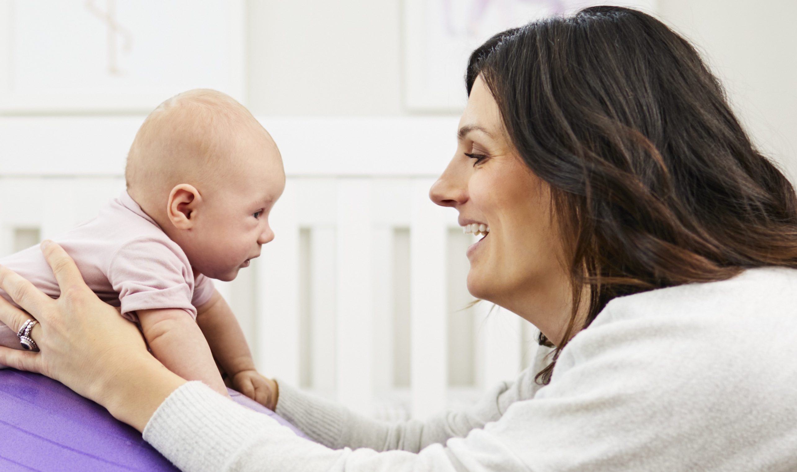 Baby doing tummy time on an exercise ball being supported by a woman