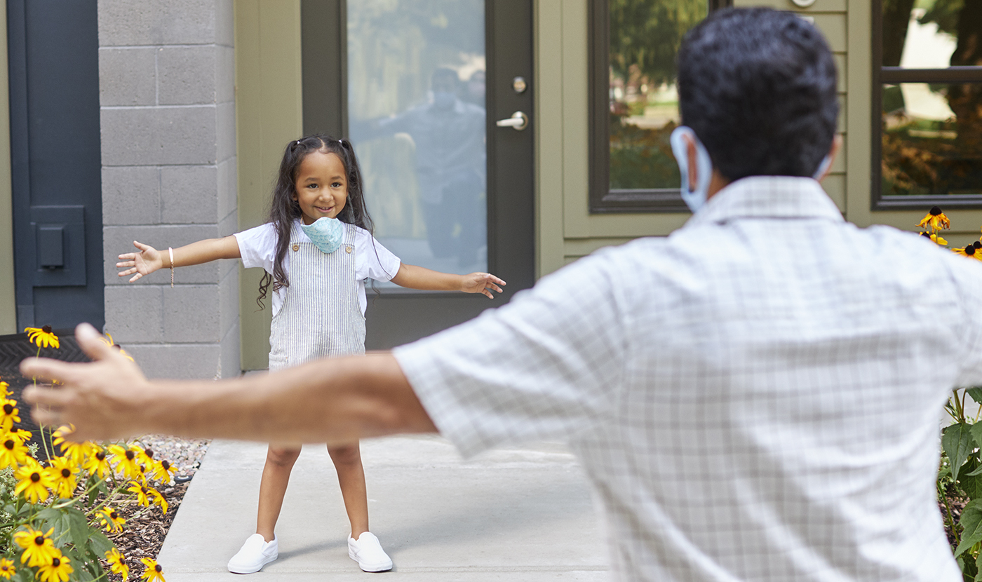 A little girl gives her relative a hug from a safe distance.