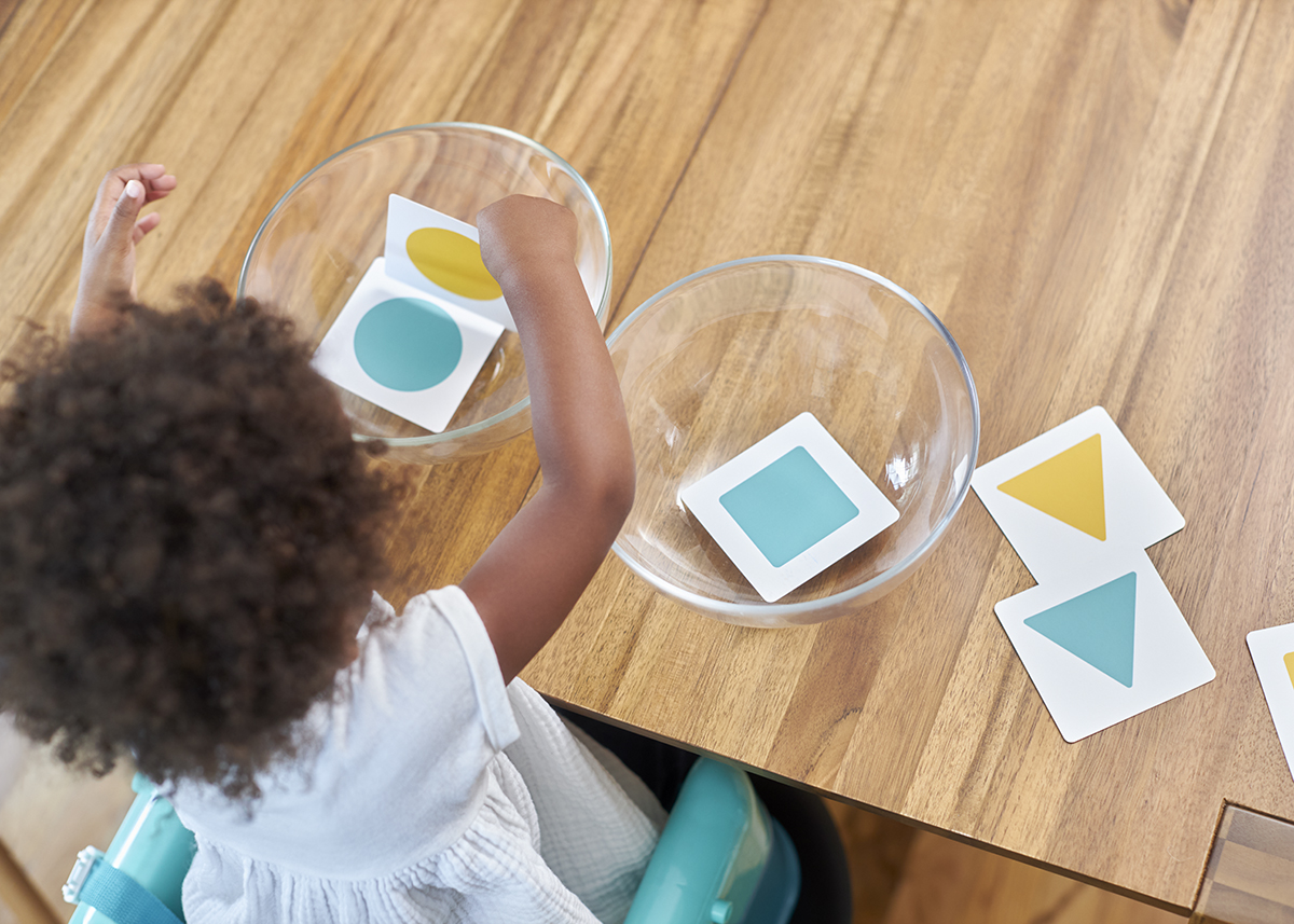 Toddler sorting different colors and patterns into two mixing bowls