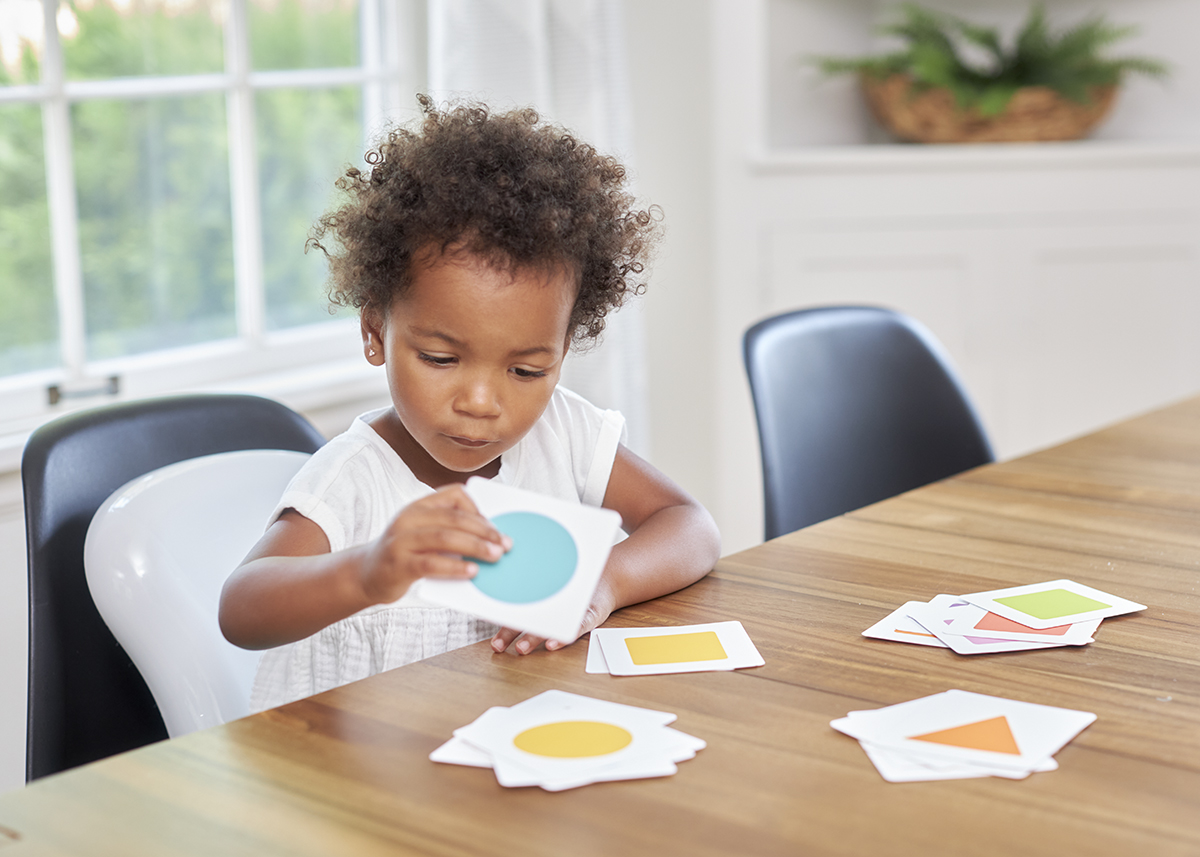 Toddler sorting different colors and patterns on the kitchen table
