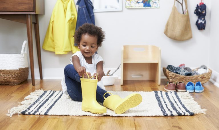 Little girl puts on her own boots.