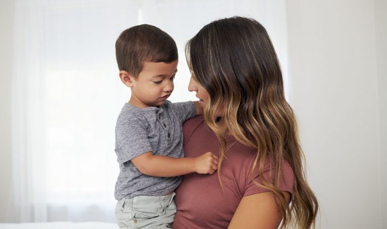 Mother holds her toddler while speaking to him.