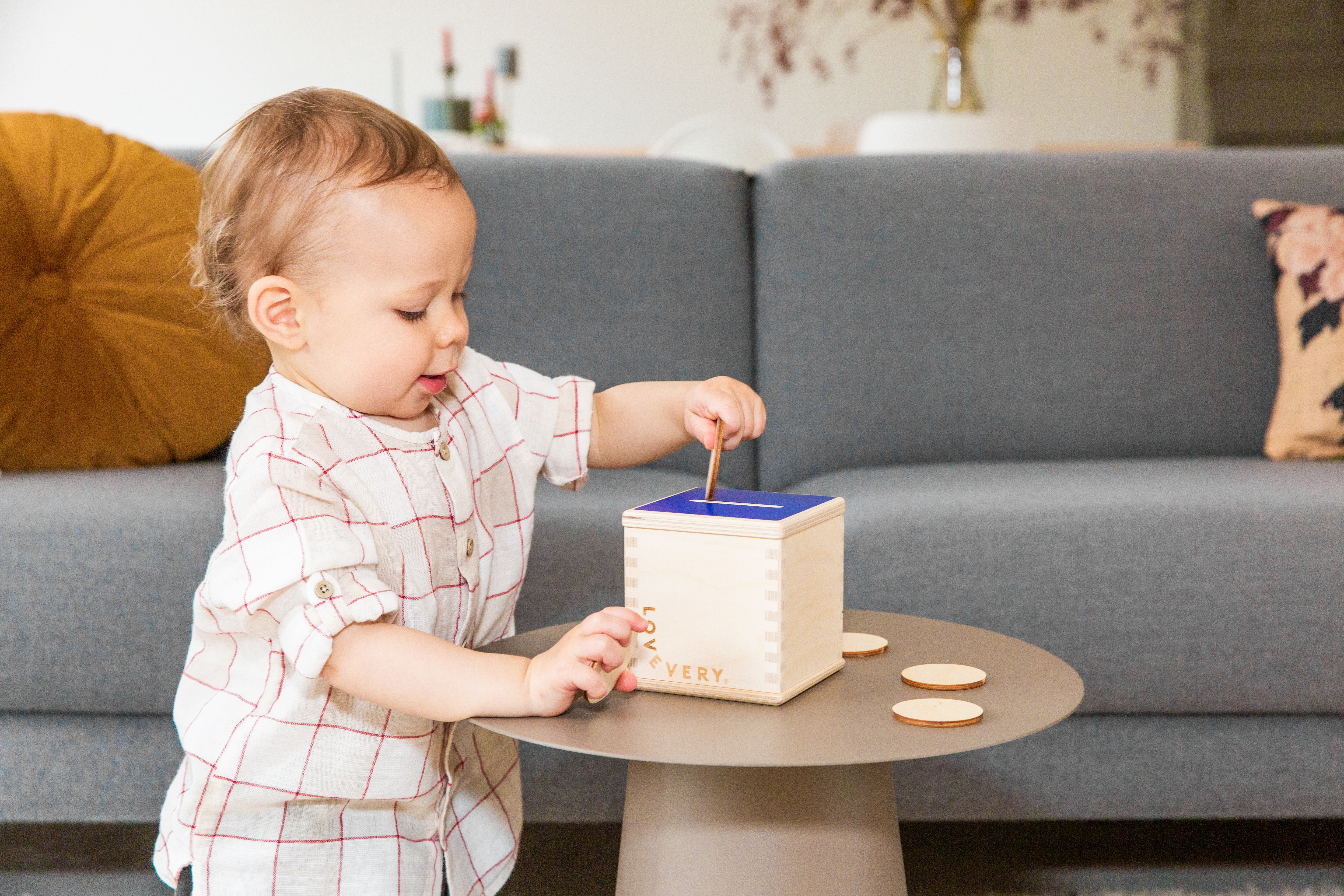 Toddler playing with a Lovevery Wooden Coin Box