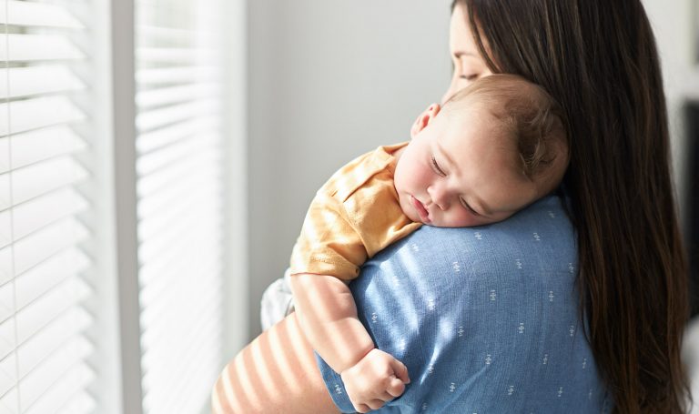 Mother cradles her sleeping baby.