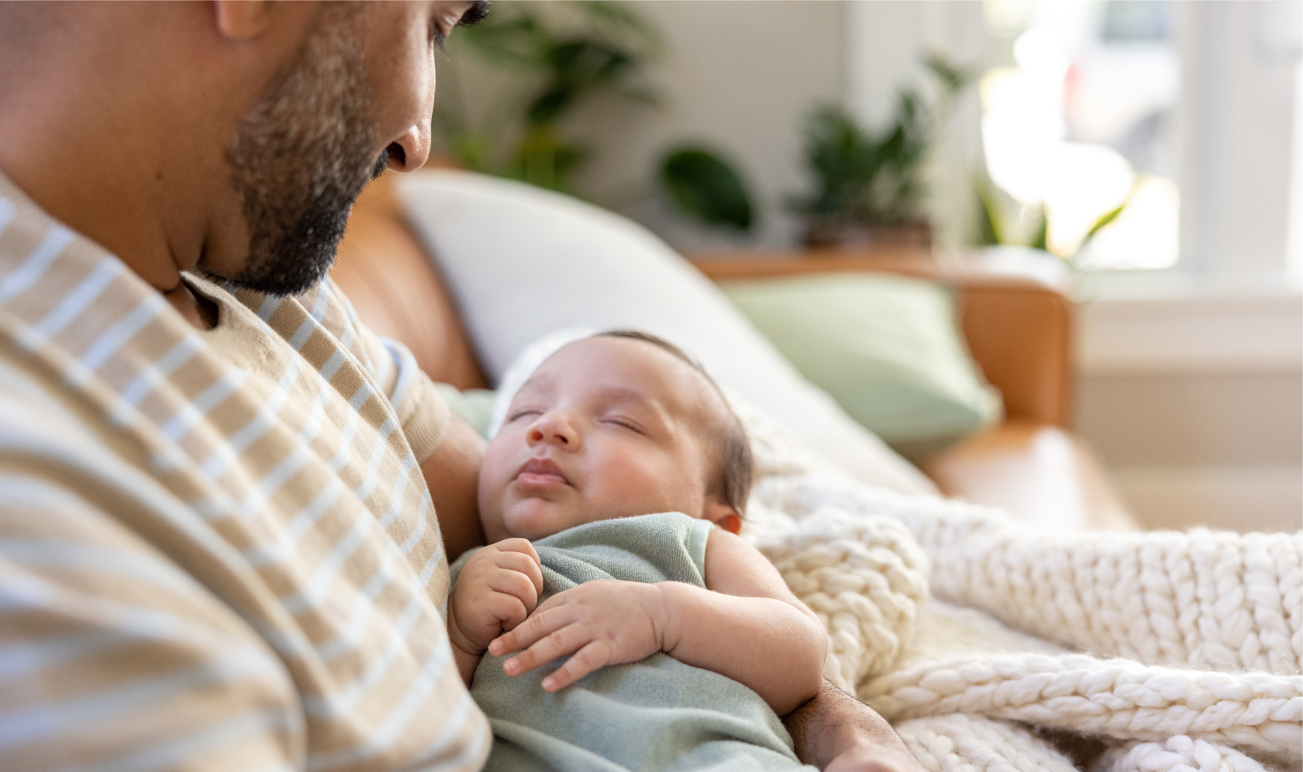 Dad looks lovingly at sleeping baby.