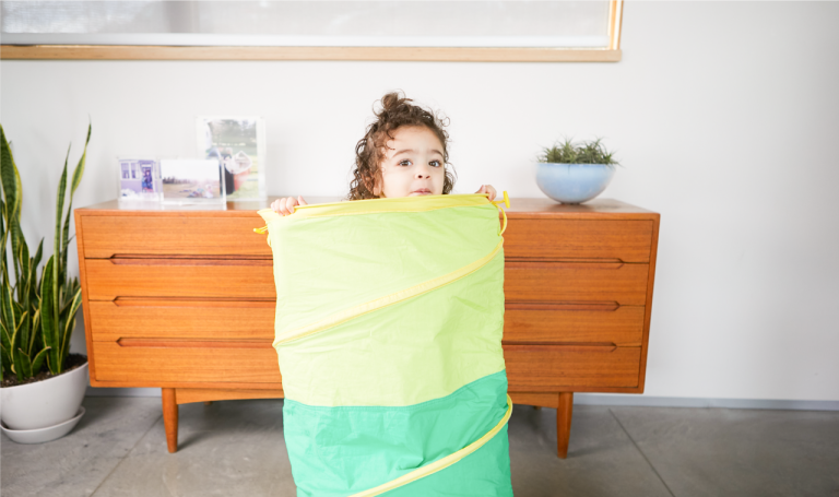 Child peaks out of Lovevery play tunnel.